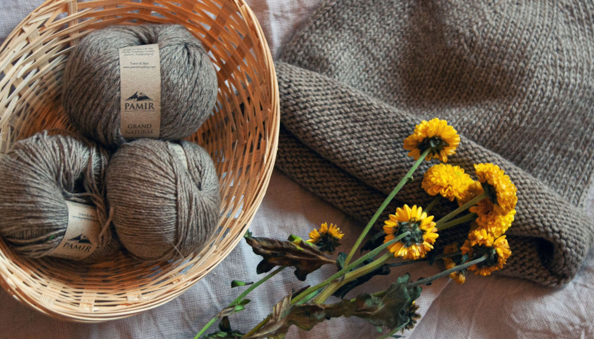 Kaschmirknäuel in Natural in einem Korb mit gelben Blüten