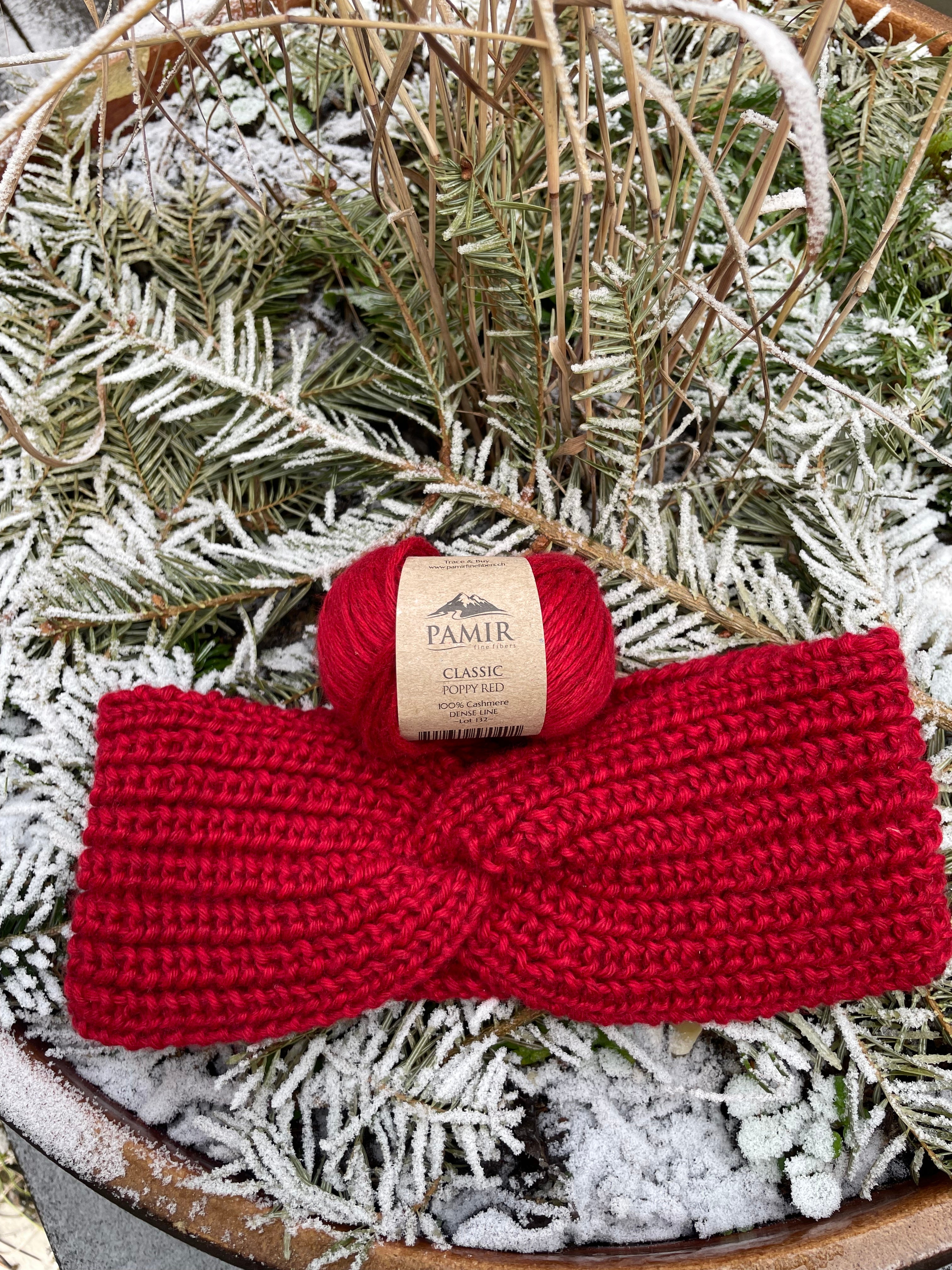 Stirnband im Halbpatent aus CLASSIC Kaschmirgarn in Poppy Red neben einem Knäuel