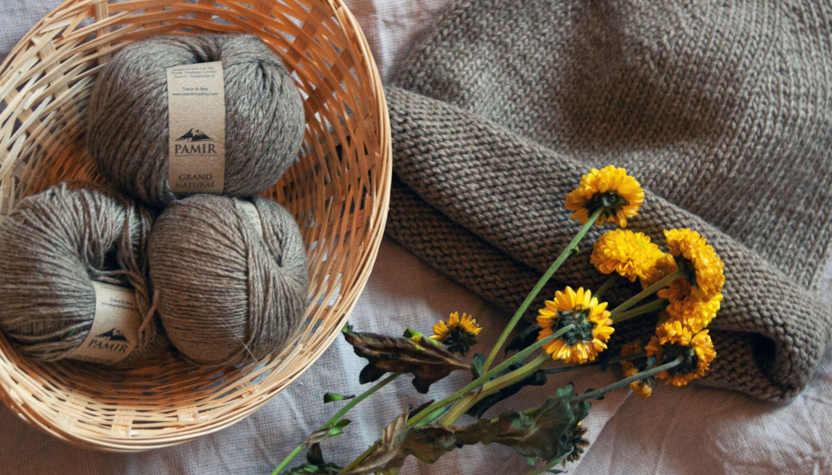 Kaschmirknäuel in Natural in einem Korb mit gelben Blüten